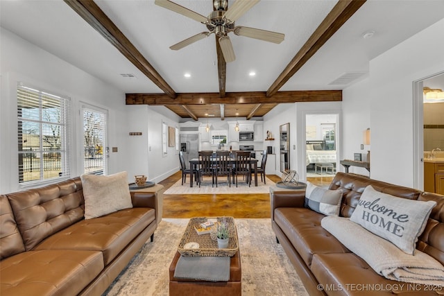 living room featuring ceiling fan, beamed ceiling, and light wood-type flooring