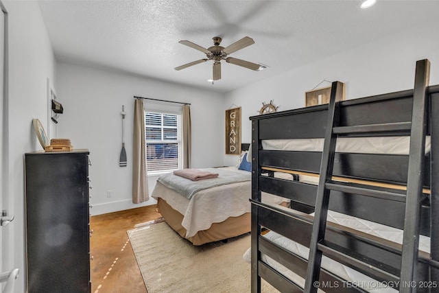 bedroom featuring ceiling fan, concrete flooring, and a textured ceiling