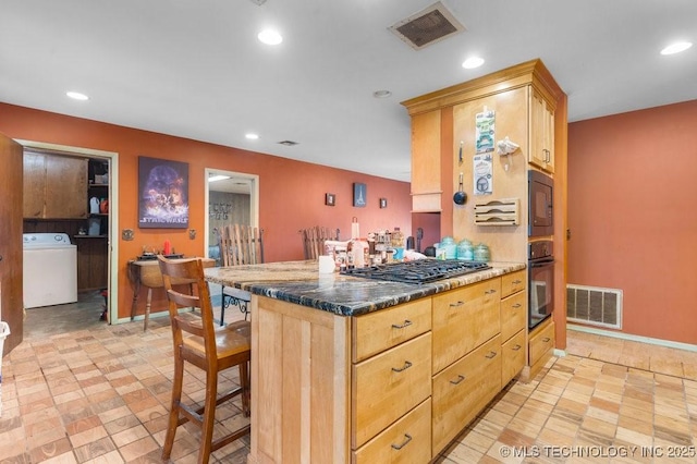 kitchen featuring light brown cabinets, washer / clothes dryer, a breakfast bar area, and black appliances