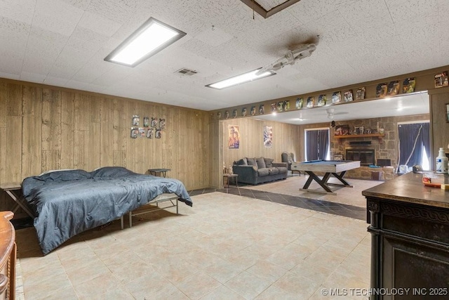 bedroom with wooden walls, a textured ceiling, and a fireplace