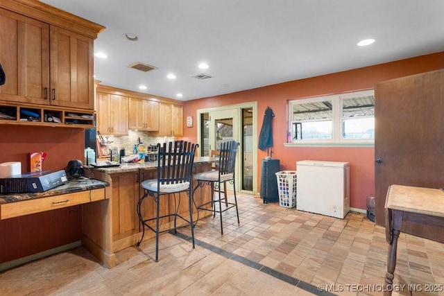 kitchen with tasteful backsplash, a kitchen breakfast bar, and refrigerator