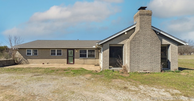 rear view of property with a yard, a patio, brick siding, and a chimney