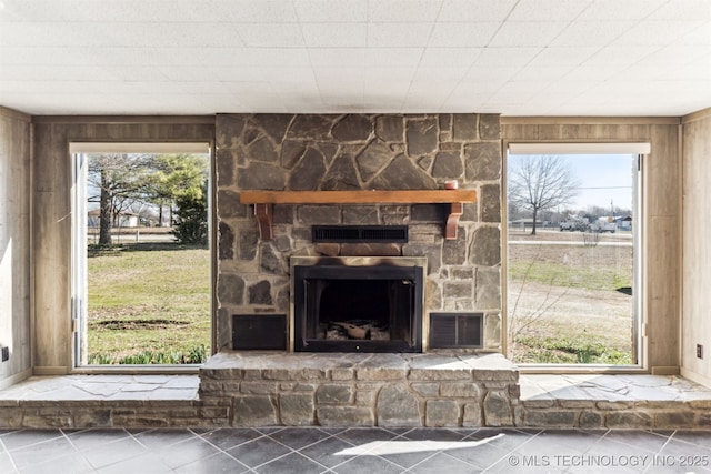 interior details with a stone fireplace, visible vents, and wood walls