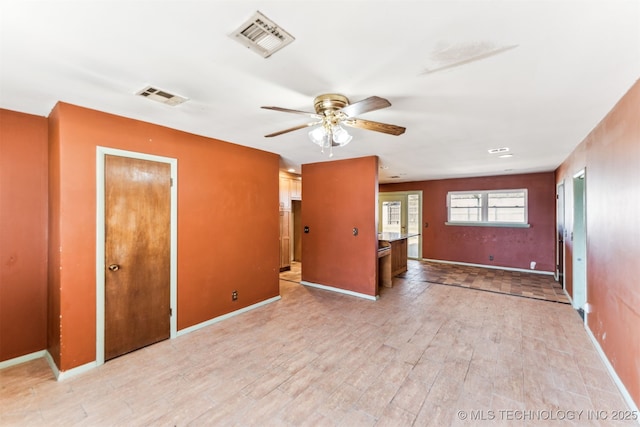 empty room featuring visible vents, light wood-style flooring, baseboards, and ceiling fan