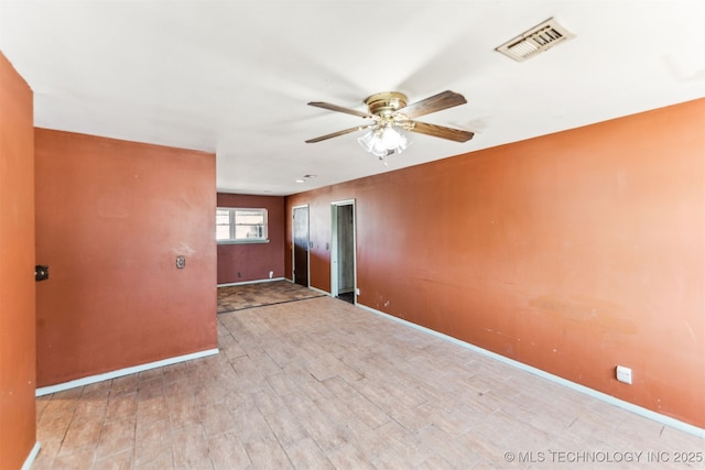 empty room with visible vents, baseboards, wood finished floors, and a ceiling fan