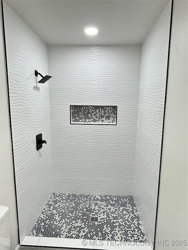 bathroom featuring tiled shower and toilet