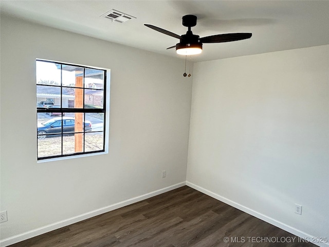 empty room with ceiling fan, a healthy amount of sunlight, and dark hardwood / wood-style flooring