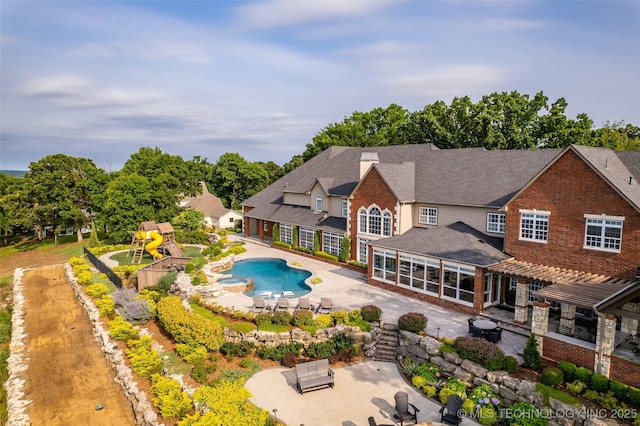 view of pool with a patio, a playground, and a sunroom