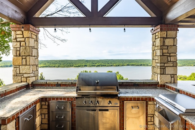 view of patio featuring exterior kitchen, a gazebo, and a water view