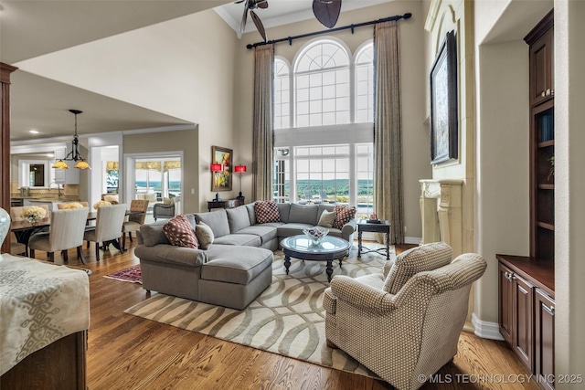 living room featuring hardwood / wood-style flooring, crown molding, and a towering ceiling