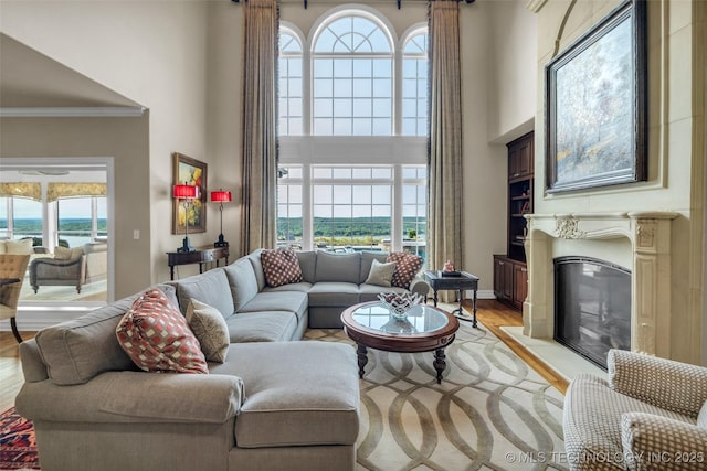 living room with crown molding, a wealth of natural light, light wood-type flooring, and a high ceiling