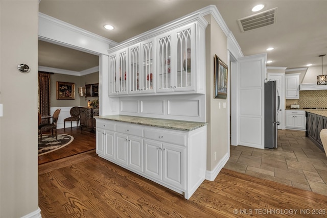 kitchen featuring ornamental molding, stainless steel refrigerator, and white cabinets