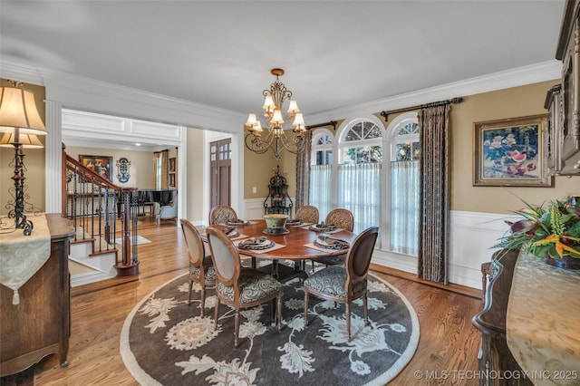 dining space with ornamental molding, a chandelier, and wood-type flooring