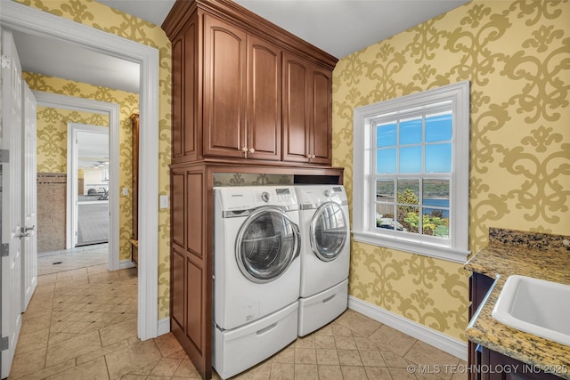 laundry area with sink, washing machine and dryer, and cabinets