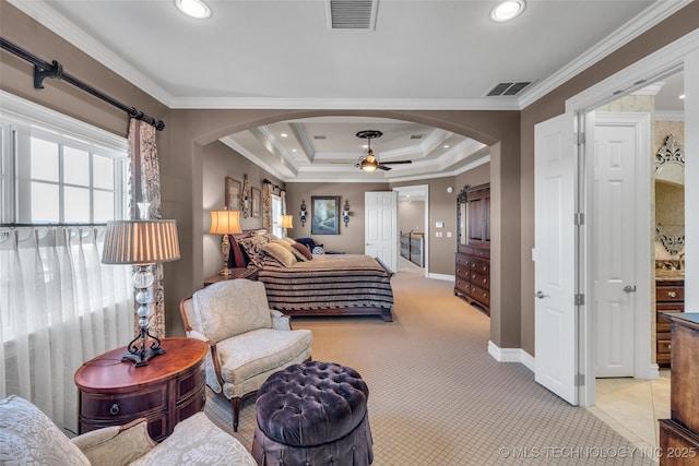 bedroom with ceiling fan, light colored carpet, ornamental molding, and a tray ceiling