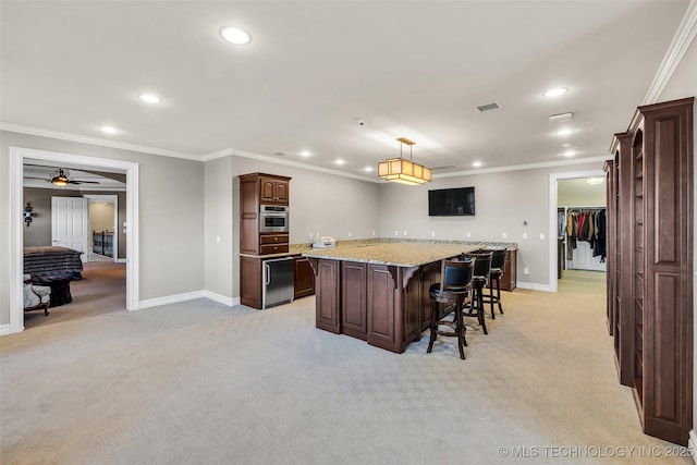 kitchen with dark brown cabinetry, hanging light fixtures, ornamental molding, a kitchen island, and light colored carpet