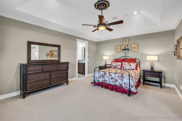 carpeted bedroom with a raised ceiling, ornamental molding, ceiling fan, and ensuite bath