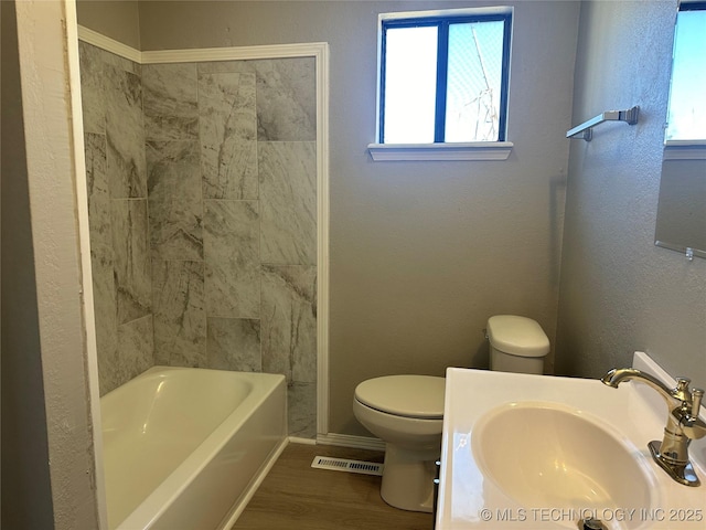 full bathroom with sink, wood-type flooring, tub / shower combination, and toilet