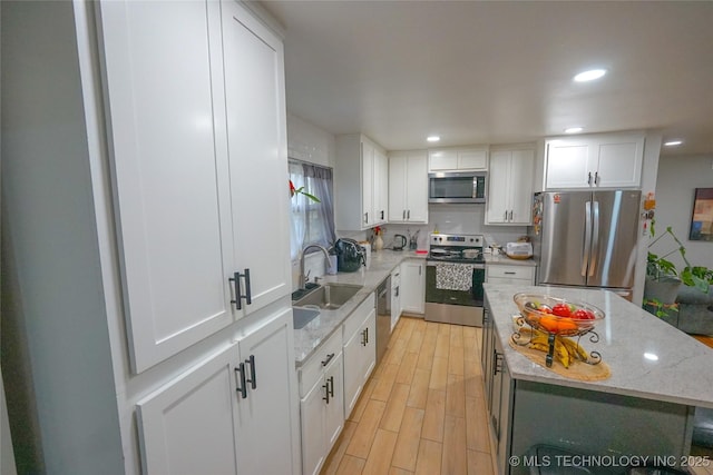 kitchen featuring white cabinetry, stainless steel appliances, a center island, and sink