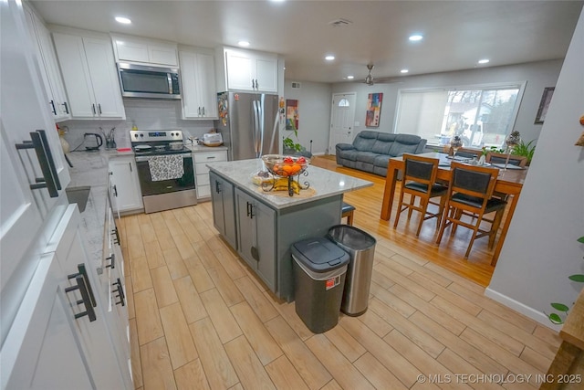 kitchen featuring white cabinetry, light hardwood / wood-style flooring, a center island, and appliances with stainless steel finishes