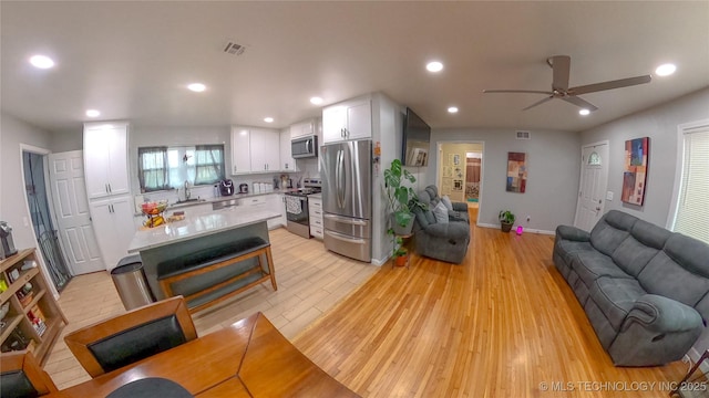 living room with ceiling fan, sink, and light hardwood / wood-style floors