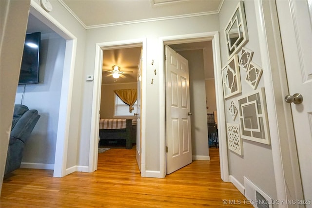 corridor featuring crown molding and light hardwood / wood-style flooring