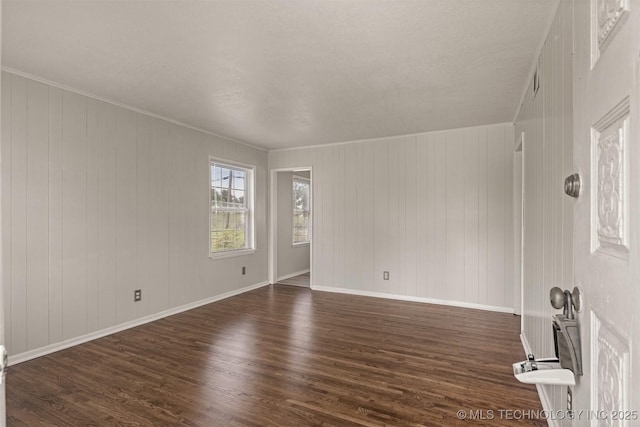 empty room with ornamental molding and dark hardwood / wood-style floors