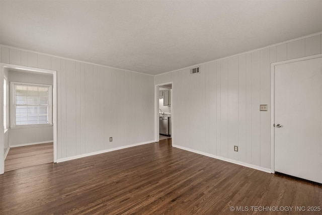 empty room with ornamental molding and dark hardwood / wood-style floors