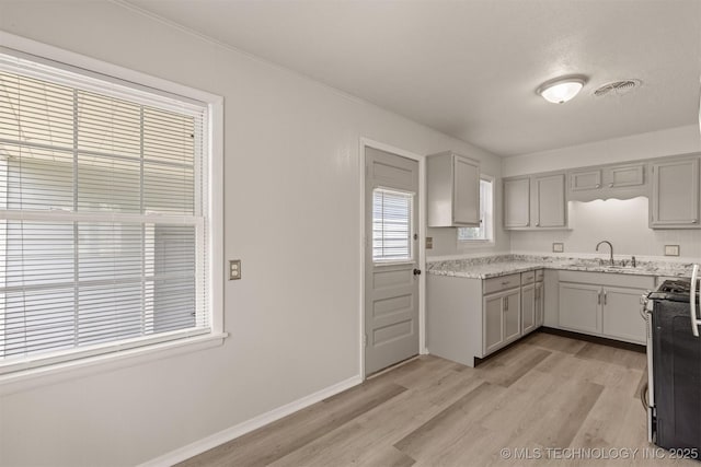 kitchen featuring sink, gray cabinetry, stainless steel range, and light hardwood / wood-style floors