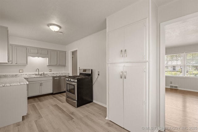 kitchen with appliances with stainless steel finishes, sink, light hardwood / wood-style flooring, and gray cabinetry