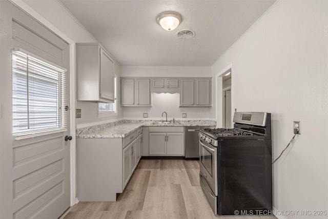 kitchen with sink, gray cabinetry, ornamental molding, light hardwood / wood-style floors, and stainless steel appliances