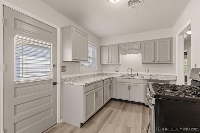 kitchen featuring gray cabinets, stainless steel gas range, sink, and light wood-type flooring