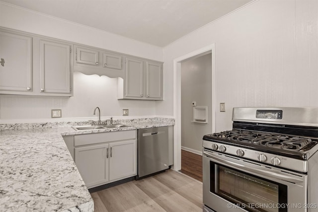 kitchen with appliances with stainless steel finishes, sink, gray cabinetry, and light hardwood / wood-style flooring