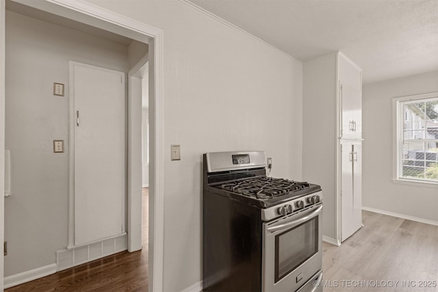 kitchen featuring white cabinets, stainless steel range with gas stovetop, and light wood-type flooring