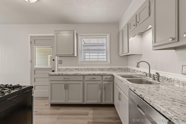 kitchen featuring sink, dishwasher, gray cabinetry, light hardwood / wood-style floors, and gas range oven