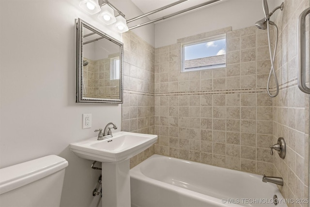 bathroom featuring tiled shower / bath combo and toilet