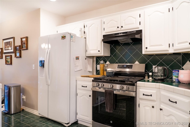 kitchen featuring stainless steel gas range, white cabinetry, backsplash, white refrigerator with ice dispenser, and tile counters