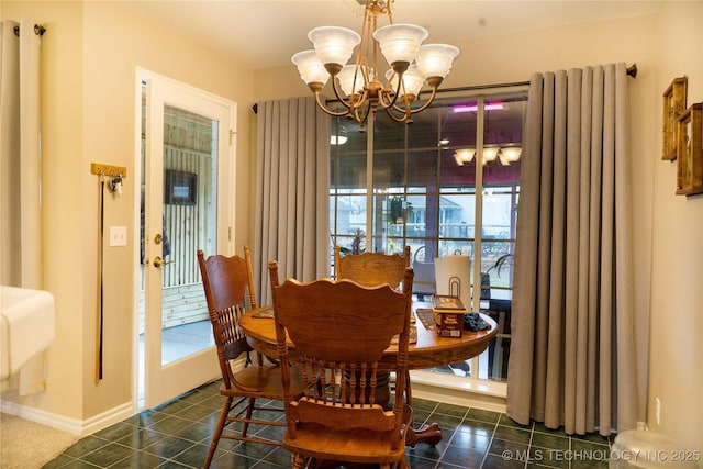 dining area with dark tile patterned flooring and an inviting chandelier