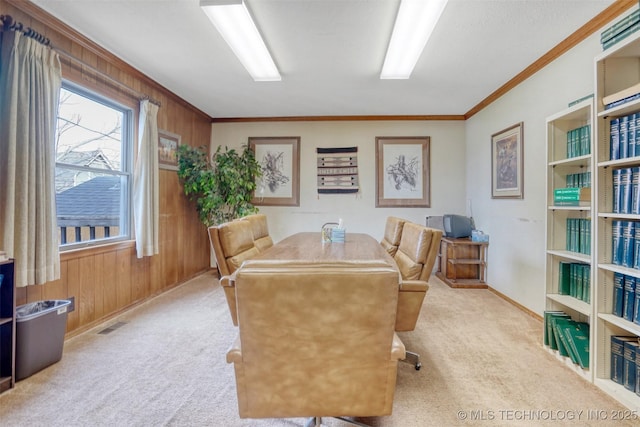 carpeted dining area featuring crown molding and wooden walls