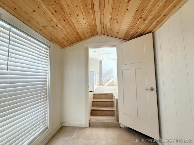 hallway with light tile patterned flooring, vaulted ceiling, wooden ceiling, wooden walls, and a wealth of natural light