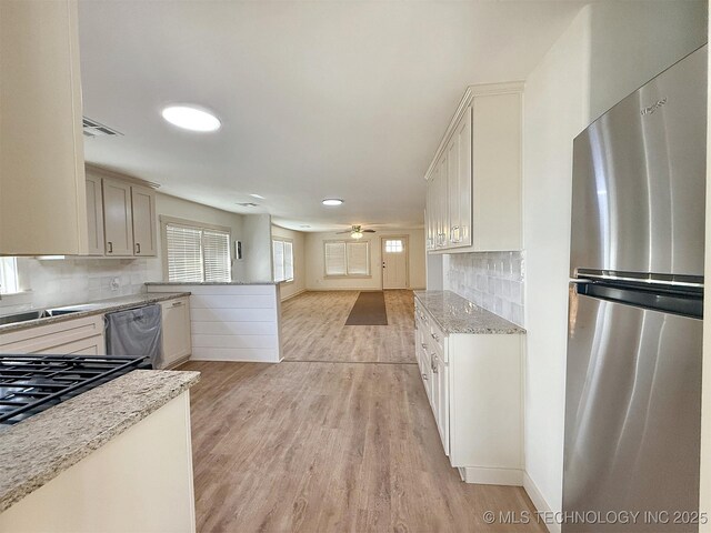 kitchen featuring light stone counters, appliances with stainless steel finishes, ceiling fan, light hardwood / wood-style floors, and white cabinets