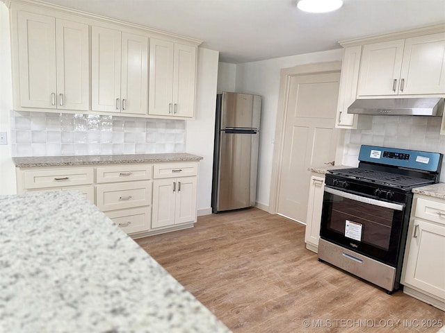 kitchen featuring light stone counters, appliances with stainless steel finishes, light hardwood / wood-style flooring, and backsplash