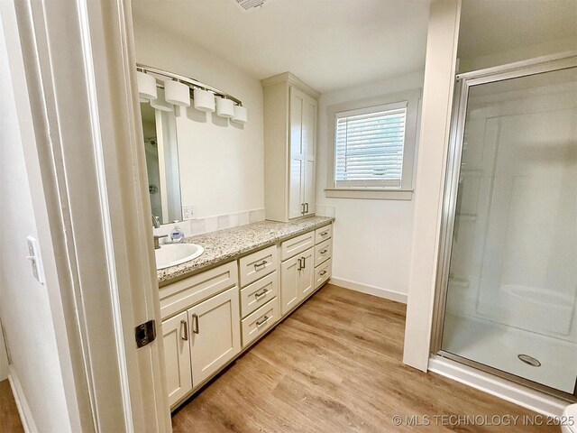 bathroom with vanity, hardwood / wood-style floors, and a shower with shower door