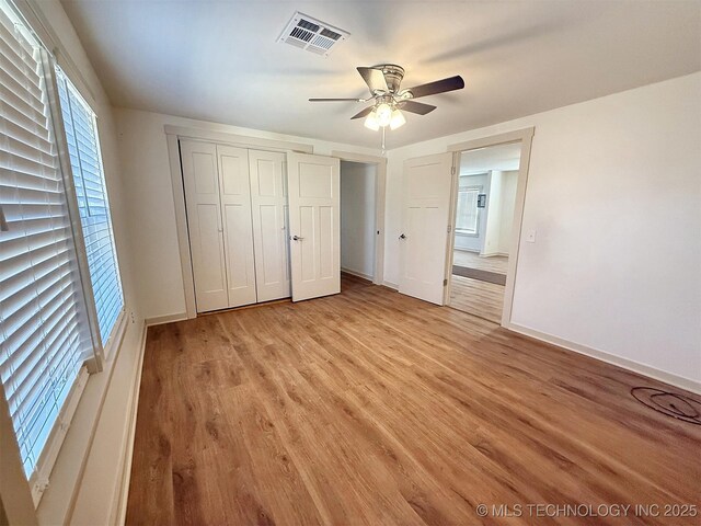 unfurnished bedroom featuring light hardwood / wood-style floors, a closet, and ceiling fan