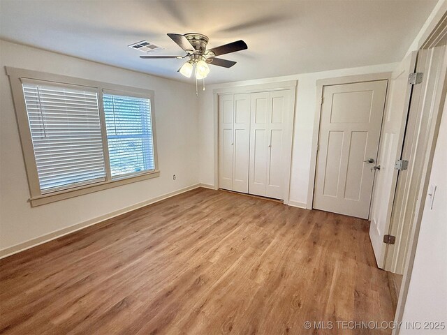 unfurnished bedroom with ceiling fan, light wood-type flooring, and a closet