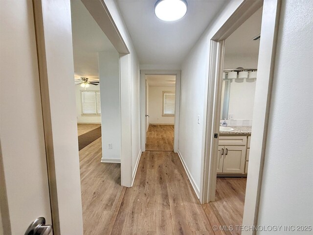 corridor featuring sink and light hardwood / wood-style floors