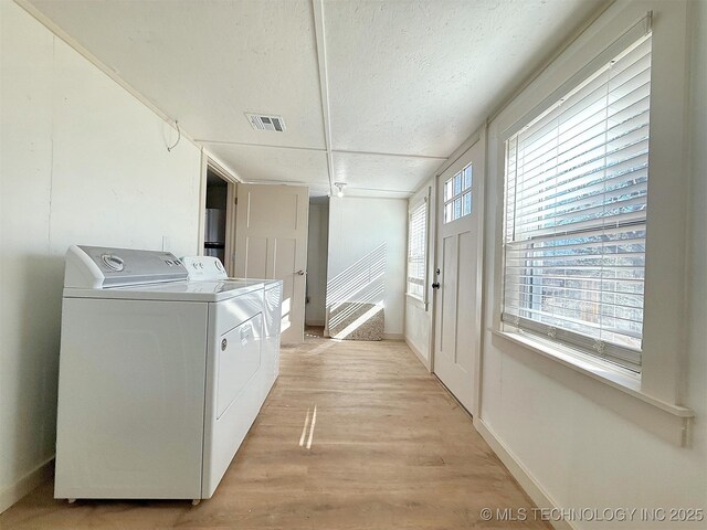 washroom featuring separate washer and dryer, a textured ceiling, and light hardwood / wood-style floors