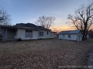 back house at dusk featuring an outbuilding