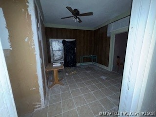 spare room featuring ceiling fan, tile patterned floors, and wood walls