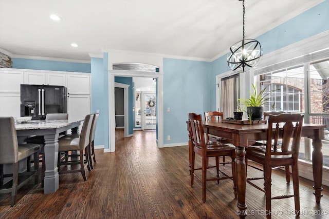 dining area with dark wood-type flooring, ornamental molding, and an inviting chandelier